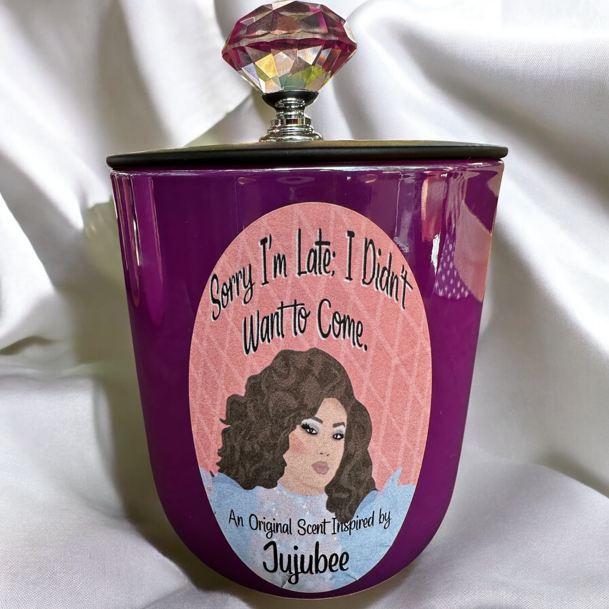 Purple candle bottle with a colorful cap and a label featuring Jujubee and text on a white background.