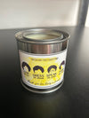 A candle with a label that reads 'Cheesecake Fixes Everything' and has various political and social statements.