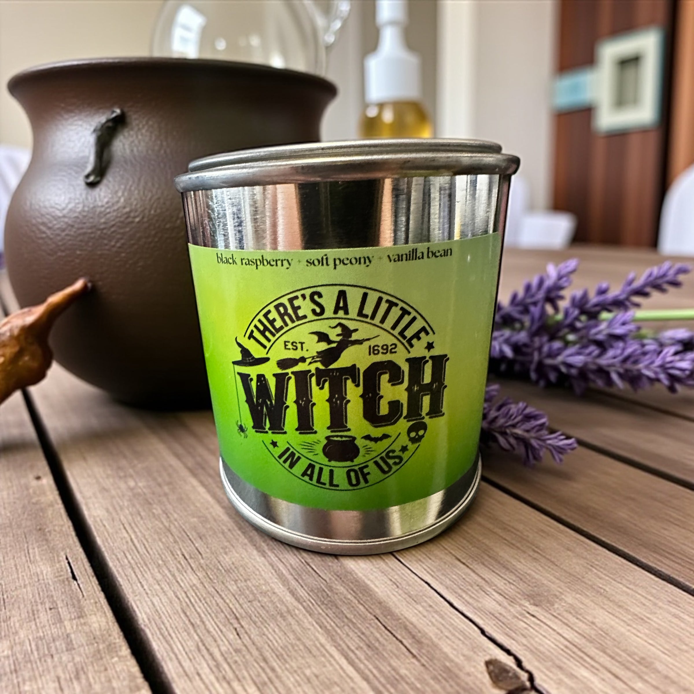 Green tumbler with 'There's a Little Witch in All of Us' text on a wooden surface with lavender and a pot.