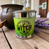 Green tumbler with 'There's a Little Witch in All of Us' text on a wooden surface with lavender and a pot.