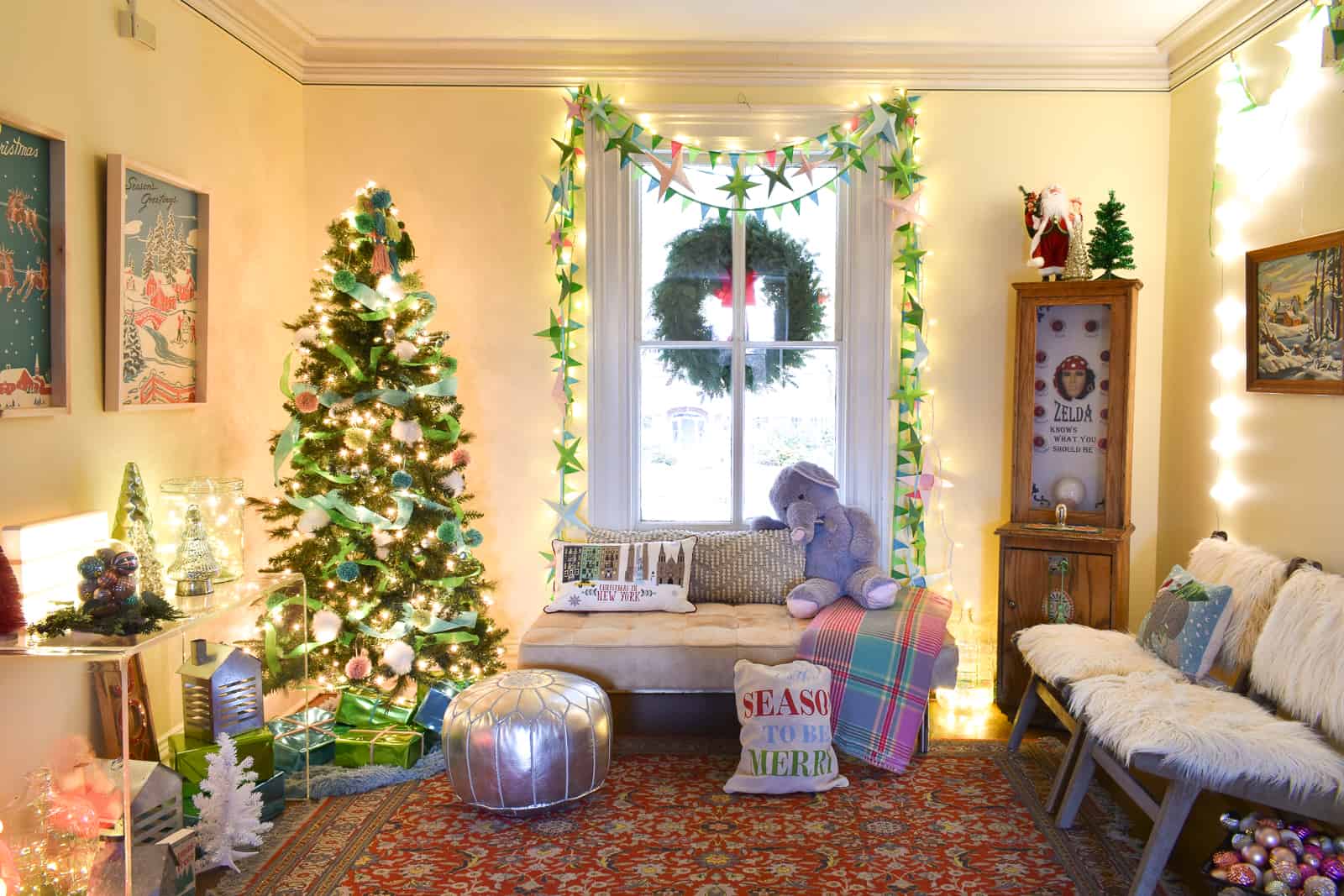 Living room decorated for Christmas with a tree, garlands, and festive pillows.