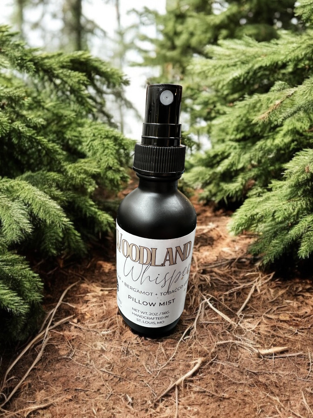 A bottle of Woodland Whisper room spray placed among pine trees.
