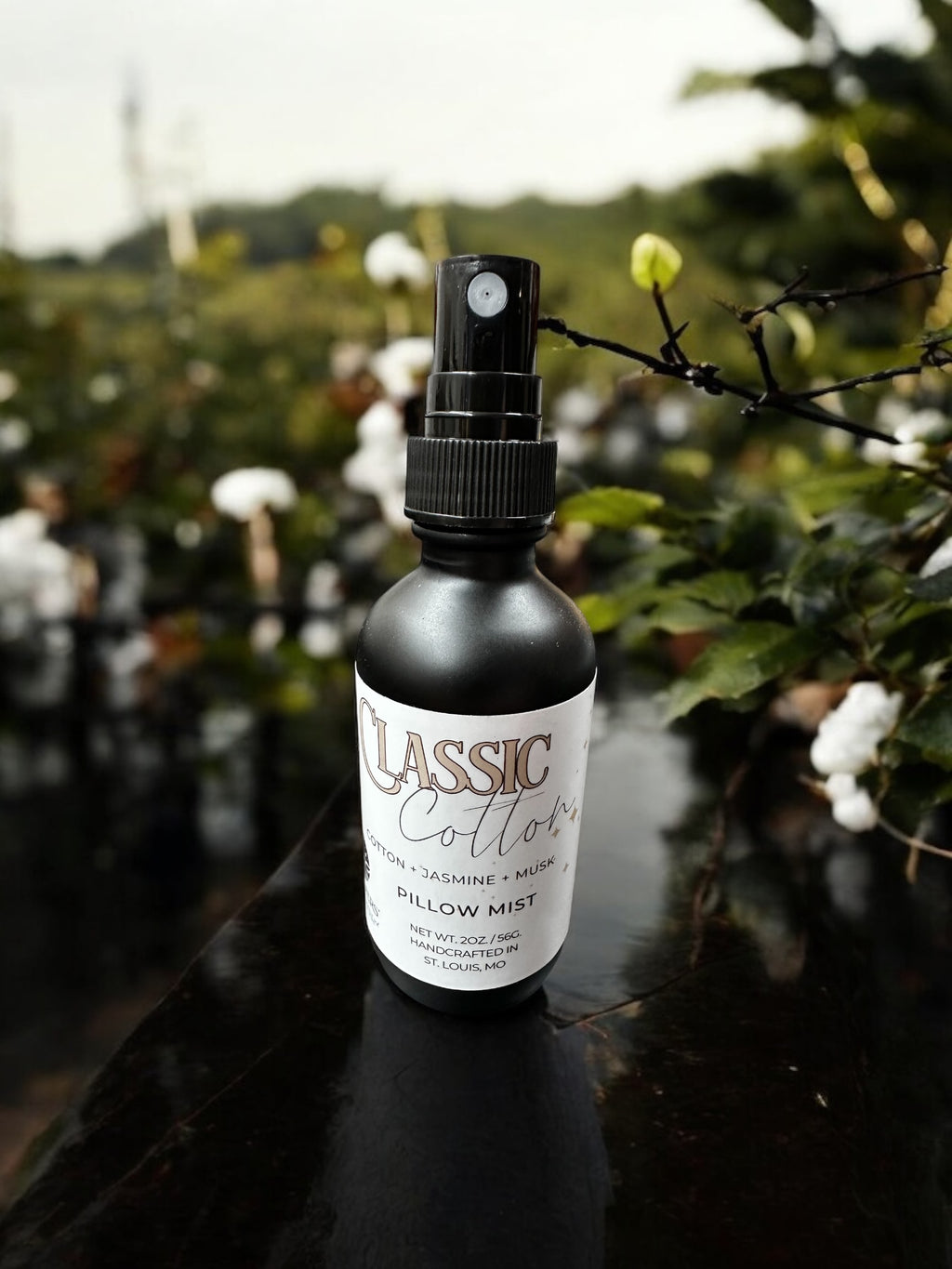 A black spray bottle labeled 'Classic Cotton' placed amidst cotton plants.