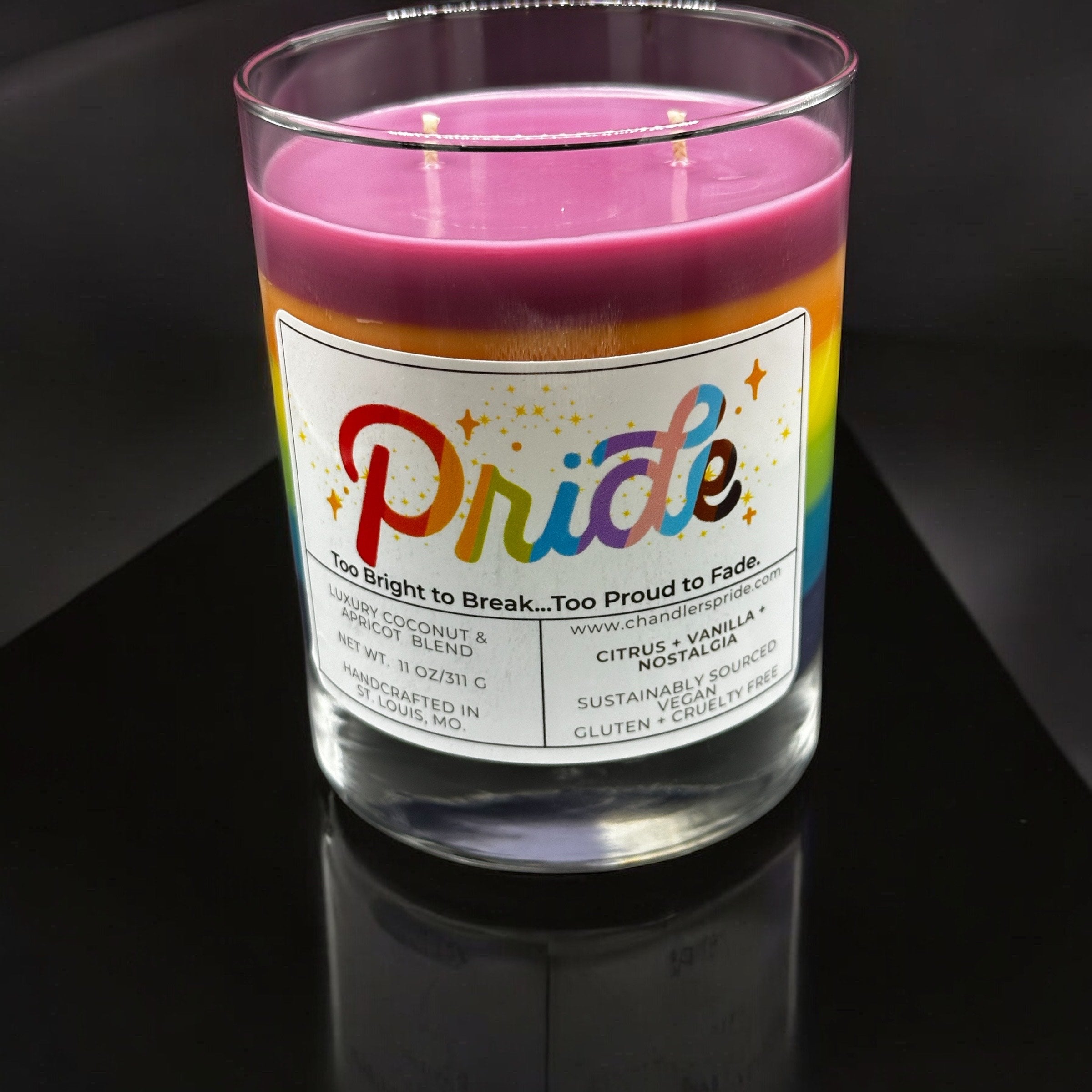 Candle with a rainbow-themed label on a black background