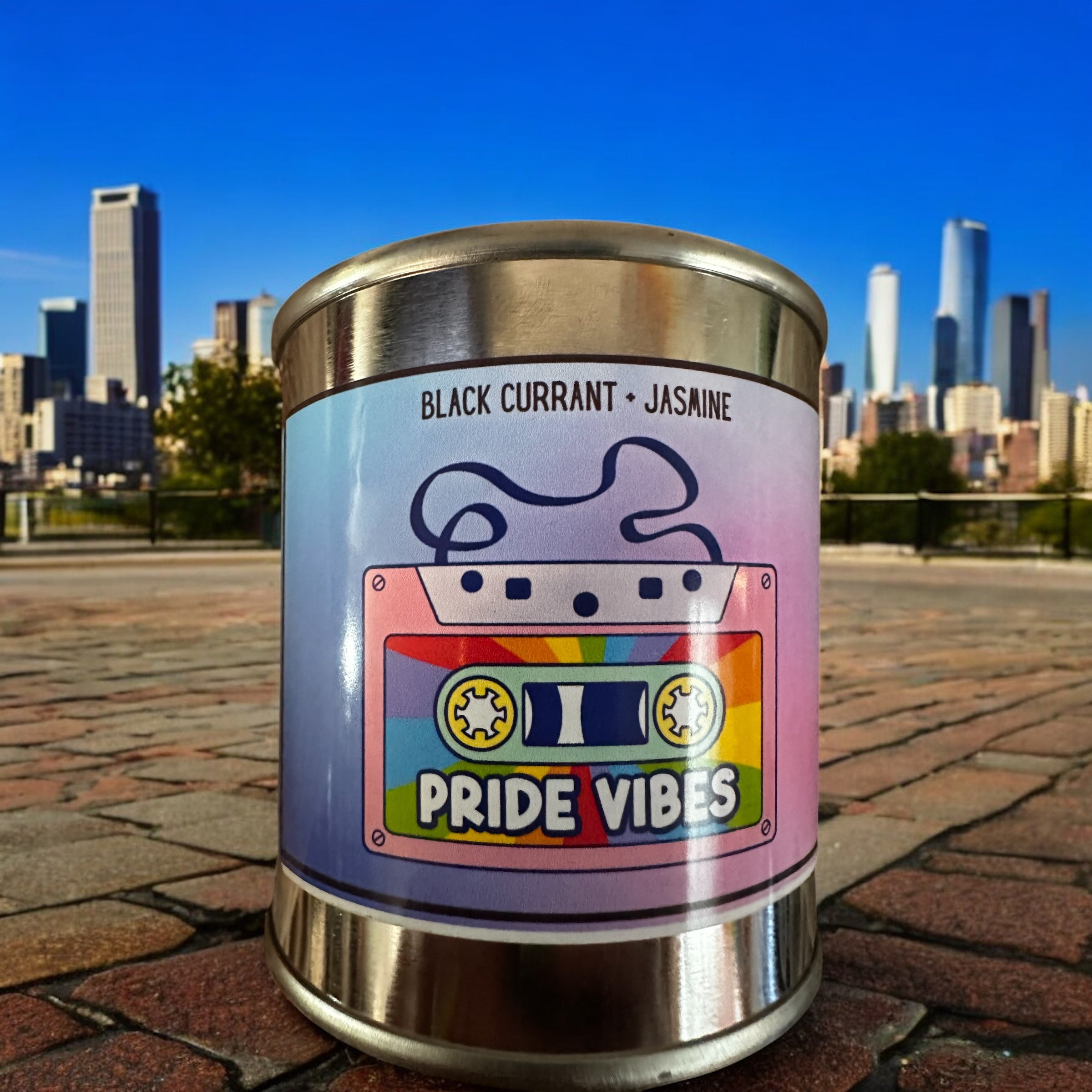 Scented candle with 'Pride Vibes' label in front of a city skyline